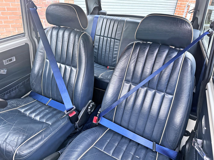 Dark blue leather seats in a classic Mini showing signs of wear and damage before the repair process.