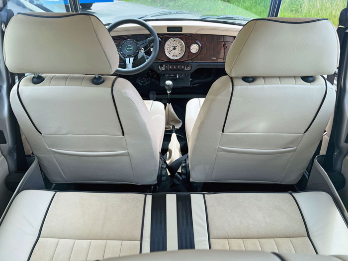 Interior view of Louisa, a classic Mini, through the rear window showcasing Alcantara and leather seats with detailed stitching.