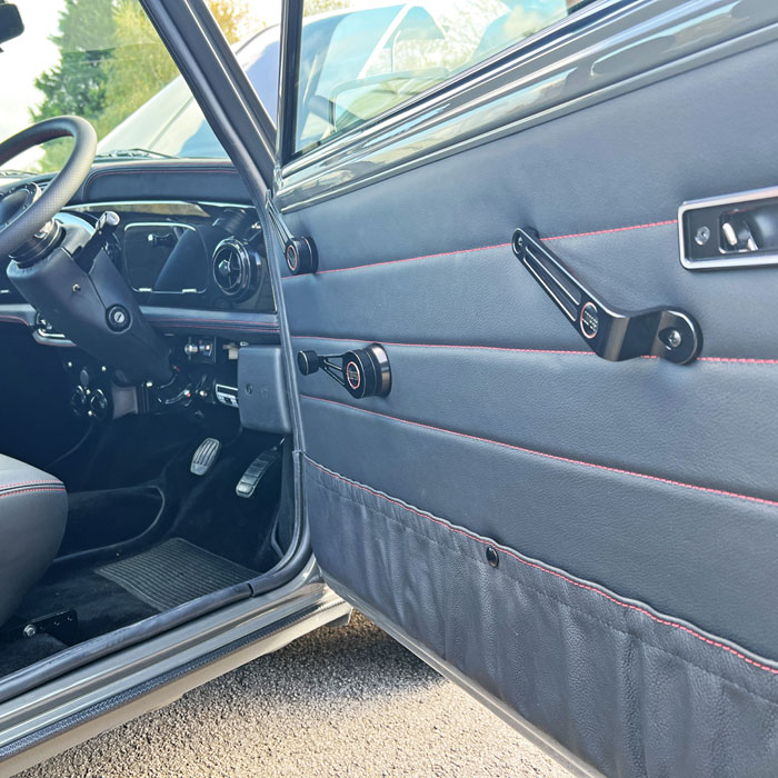 Black leather door liner in a classic Mini, accentuated with red Cooper door furniture for a custom look.
