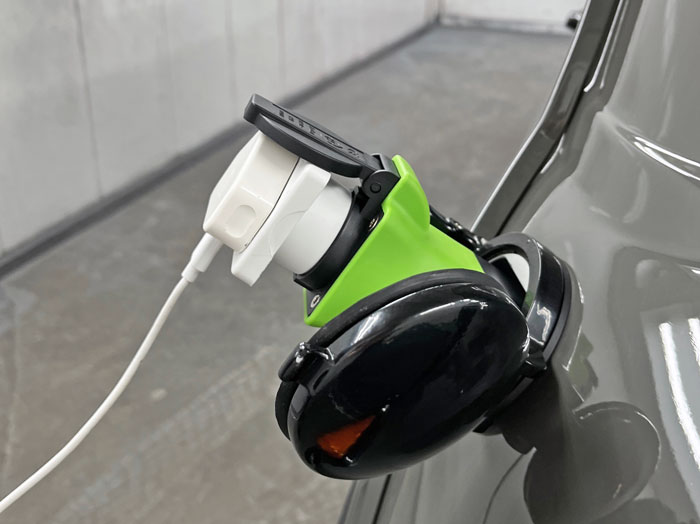 Phone charger connected to the Mini Spectre’s EV charging port for seamless device charging.