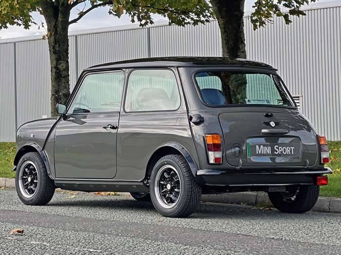 Rear view of the Mini Spectre on a tree-lined road, highlighting its black roof and custom accents.